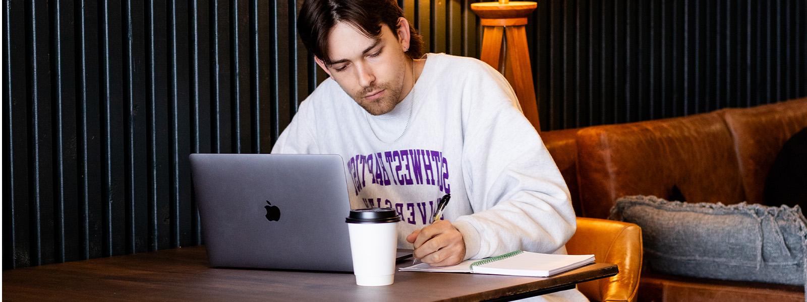 student working on computer in coffee shop